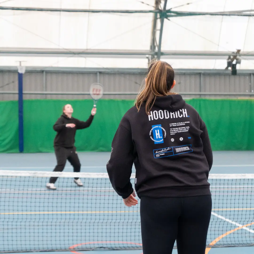 Two women playing indoor tennis.